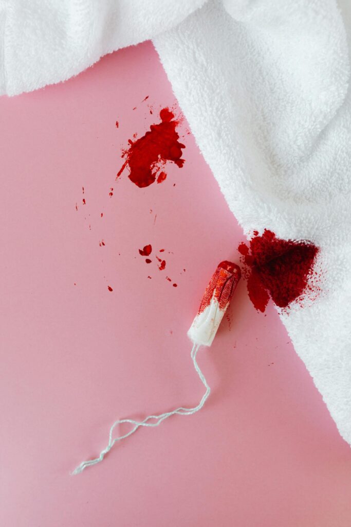 Tampon and bloody towel on pink background, symbolizing a menstrual period