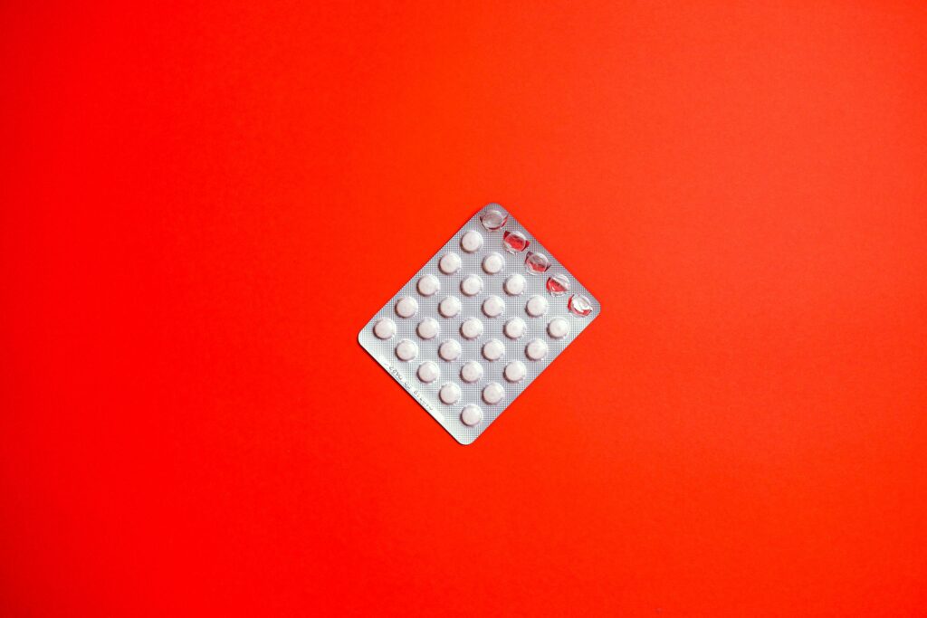 Close-up of a blister pack of pills against a solid red background symbolizing healthcare and medication.