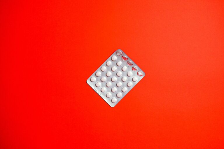Close-up of a blister pack of pills against a solid red background symbolizing healthcare and medication.